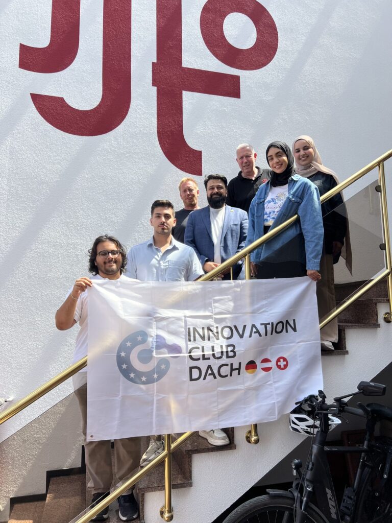 Gruppe des Innovation Club DACH mit Fahne im Treppenhaus